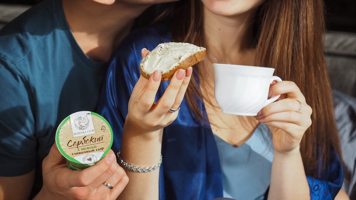 A joyful couple enjoys a cozy breakfast with bread and a warm drink, sharing smiles.